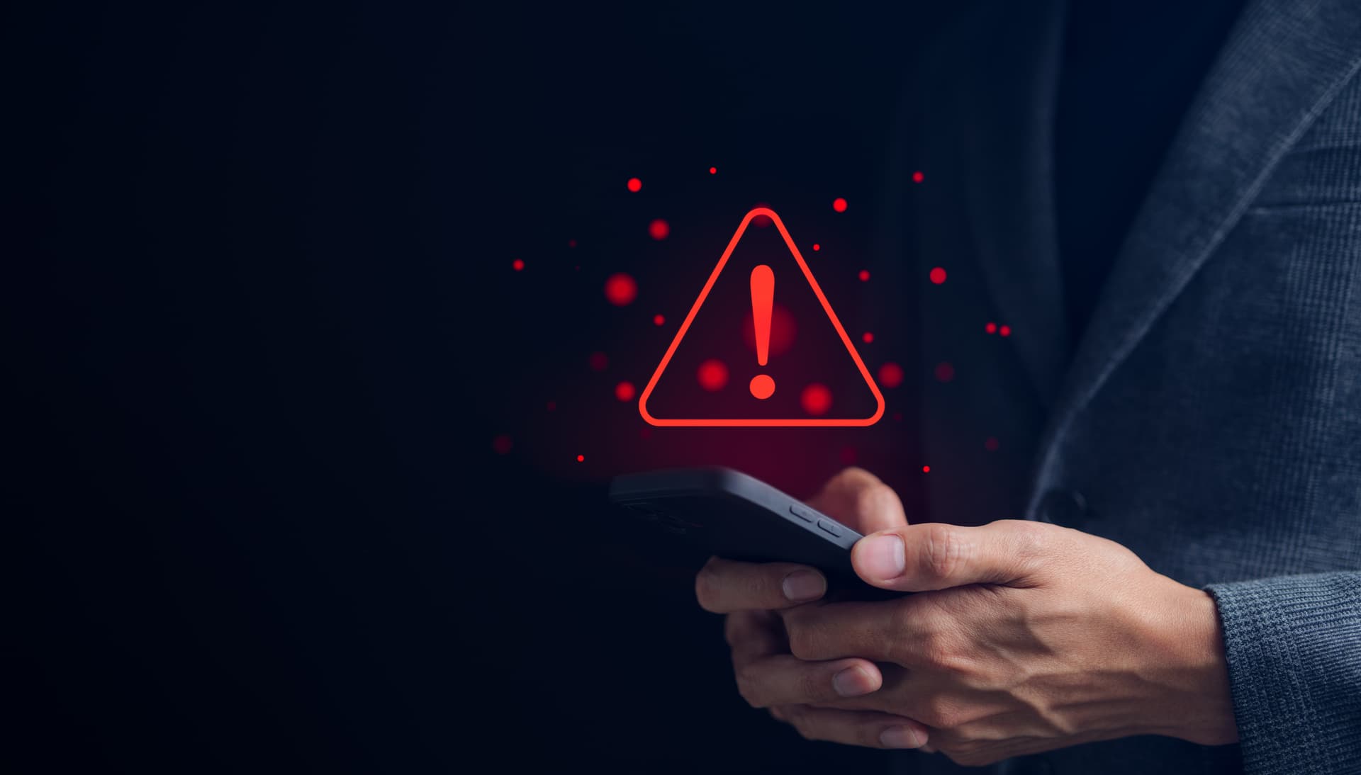 Homme tenant un téléphone affichant une alerte rouge