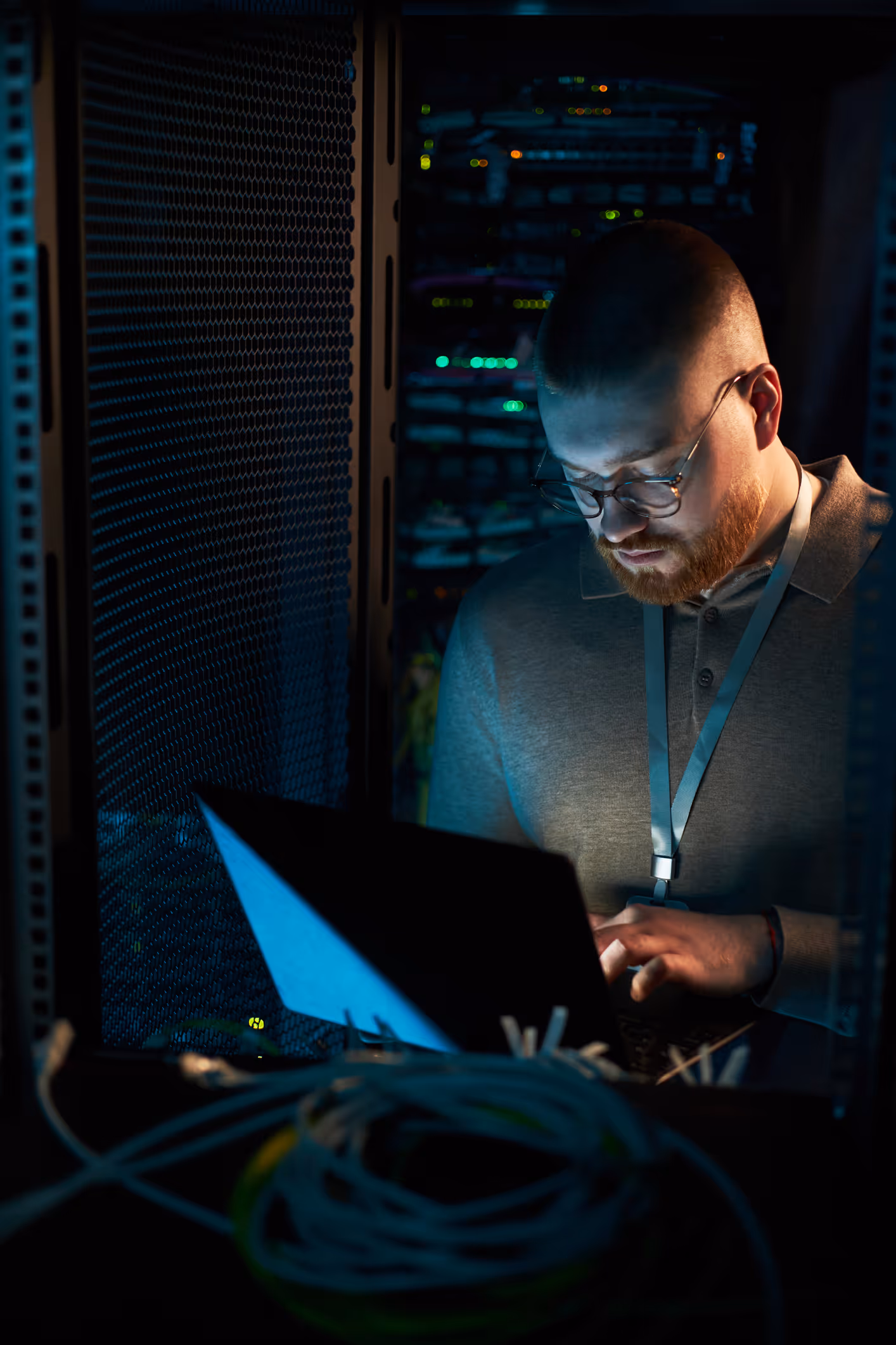 Analyste avec ordinateur portable dans une salle de serveurs sombre